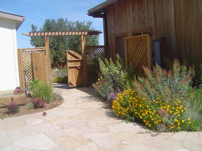 Flagstone patio leading to arbored gate and rustic barn